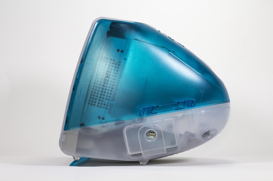 Un iMac G3 del 1998 in colore blu traslucido, visto di lato, con lo sportello delle porte aperto