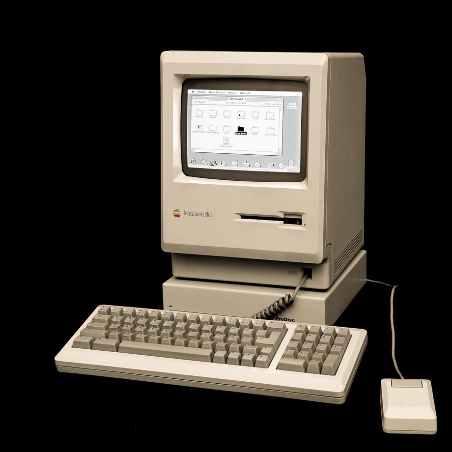 Un Macintosh Plus del 1986 con tastiera e mouse, acceso, con una finestra del Finder sullo schermo